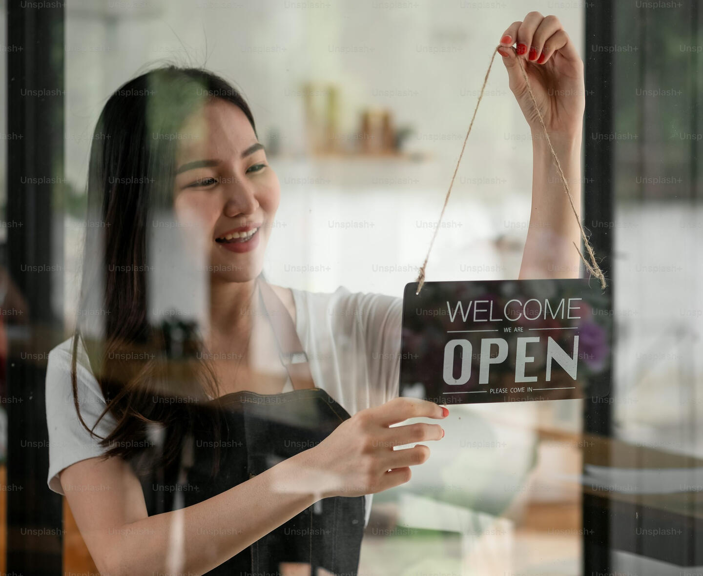 Lady Smiling Small shop owner hanging open sign for FeedbackBuddy app.